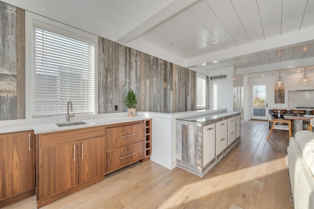101 Harvard Ave, Cape May Point, NJ 08212 - kitchen featuring beamed ceiling, brown cabinets, light wood-style flooring, a sink, and wood walls