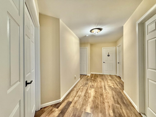 hall with light wood-style floors and baseboards