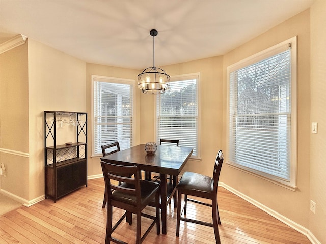 dining space featuring light wood-style floors, a notable chandelier, and baseboards