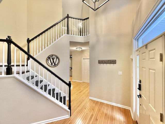 entryway featuring hardwood / wood-style floors, stairway, a high ceiling, and baseboards