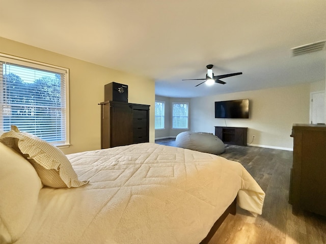 bedroom with a fireplace, visible vents, ceiling fan, wood finished floors, and baseboards