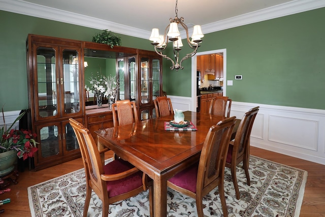 dining space with hardwood / wood-style flooring, crown molding, and a notable chandelier