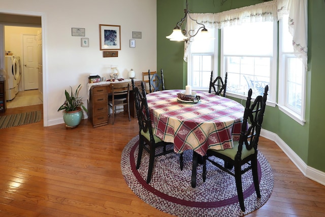 dining room with wood-type flooring, a chandelier, and washing machine and clothes dryer