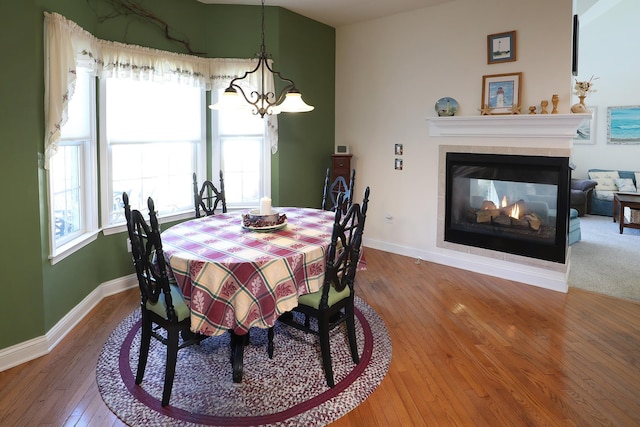 dining space featuring wood-type flooring, a chandelier, and a multi sided fireplace