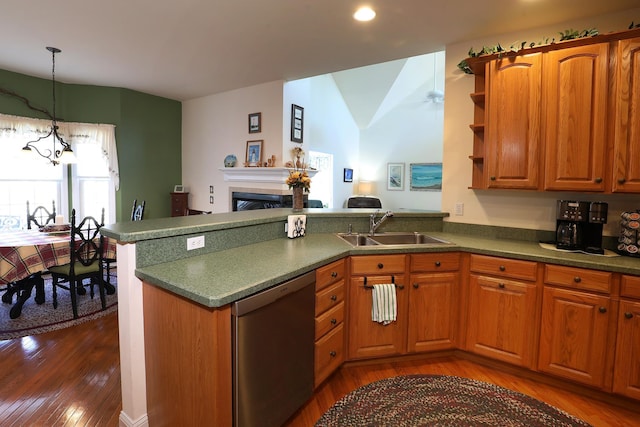 kitchen featuring dark wood-type flooring, sink, dishwasher, kitchen peninsula, and a fireplace