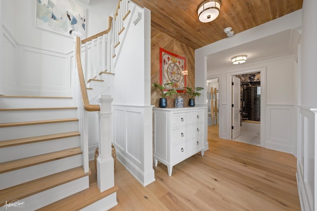 stairway with wood ceiling, wood finished floors, and a decorative wall