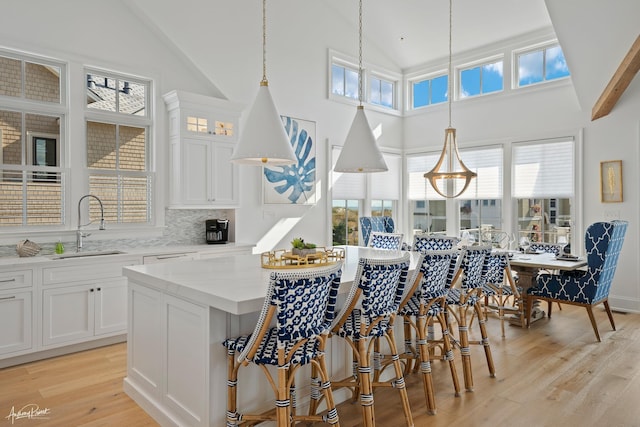 kitchen featuring white cabinetry, breakfast area, light wood finished floors, and a sink