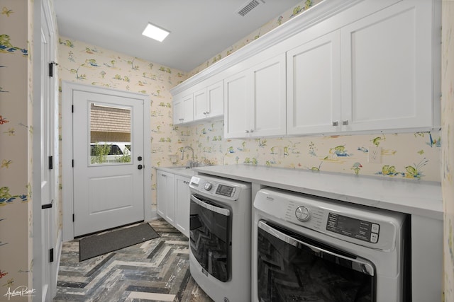 laundry area featuring visible vents, wallpapered walls, cabinet space, a sink, and washer and dryer