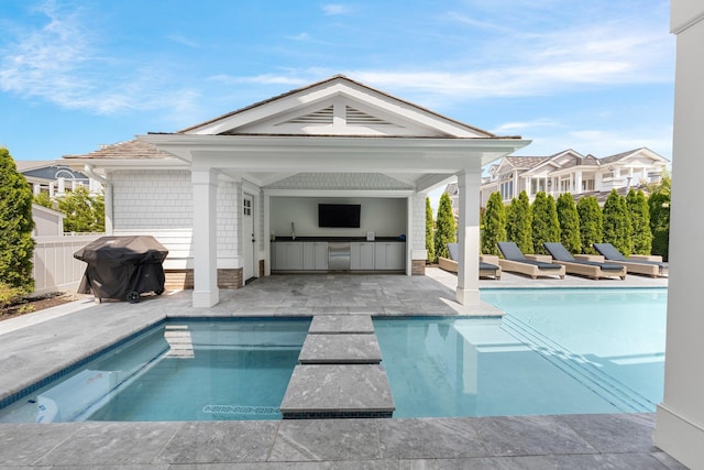 view of pool featuring fence, grilling area, exterior kitchen, a fenced in pool, and a patio area