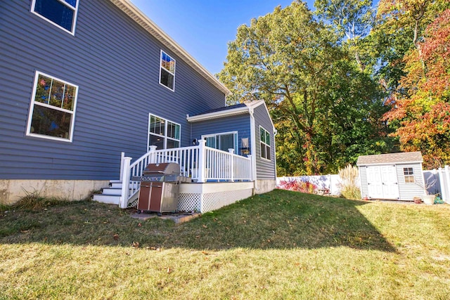 rear view of property featuring a lawn, a wooden deck, and a storage unit