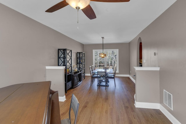 dining room with visible vents, ceiling fan, baseboards, wood finished floors, and arched walkways