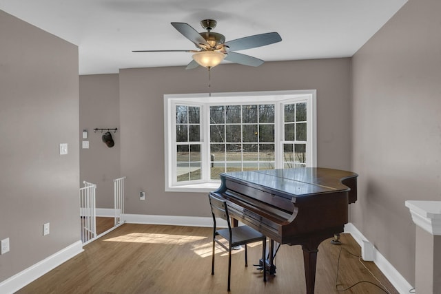 living area with a ceiling fan, baseboards, and wood finished floors