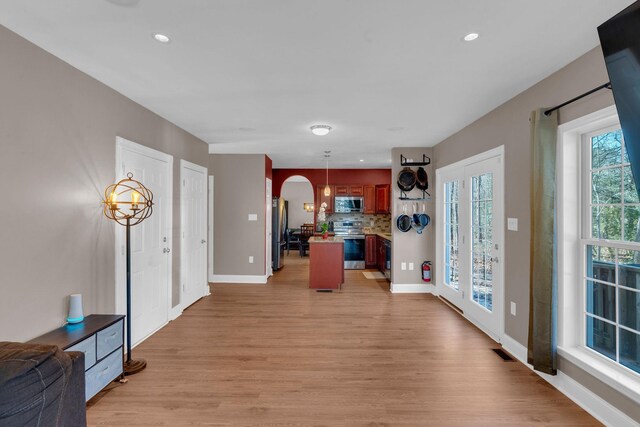 foyer entrance with visible vents, baseboards, light wood-type flooring, recessed lighting, and arched walkways