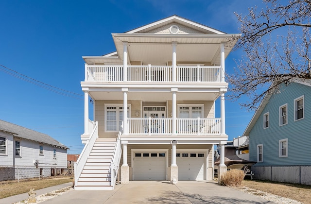 beach home with an attached garage, stairs, covered porch, a balcony, and driveway