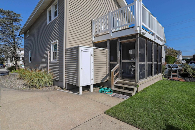 rear view of house with a patio area, a lawn, and a sunroom