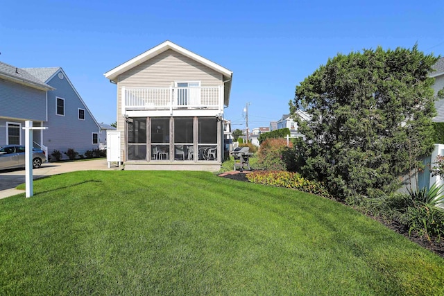 back of property featuring a yard, a balcony, and a sunroom