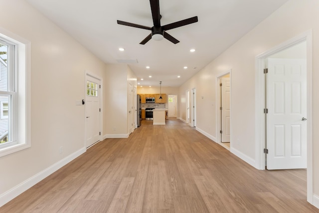 unfurnished living room with a ceiling fan, baseboards, a healthy amount of sunlight, and light wood-style floors