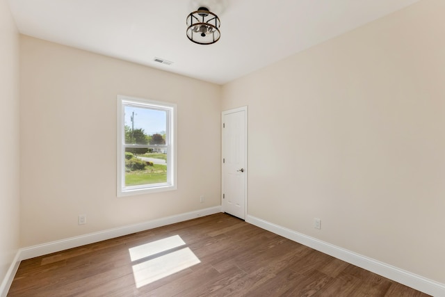 spare room featuring baseboards, wood finished floors, and visible vents