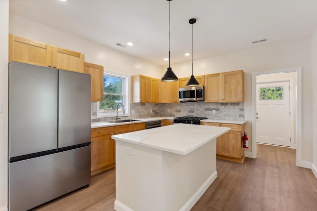 kitchen featuring visible vents, light wood-style floors, a sink, backsplash, and stainless steel appliances