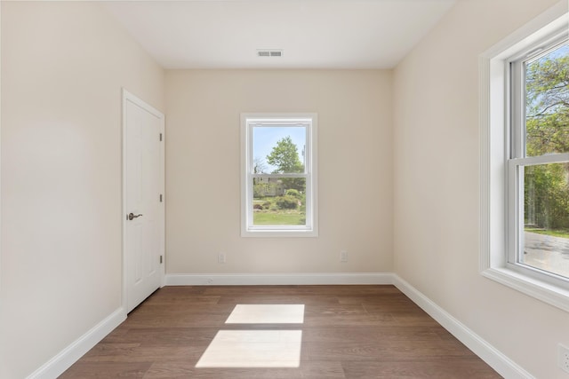 unfurnished room with visible vents, baseboards, and wood finished floors