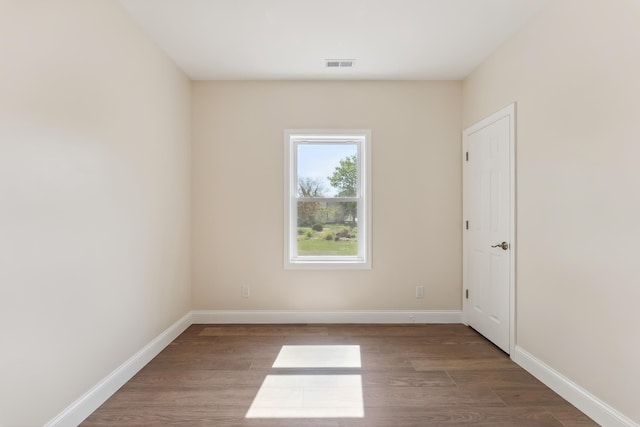 unfurnished room with baseboards, wood finished floors, and visible vents