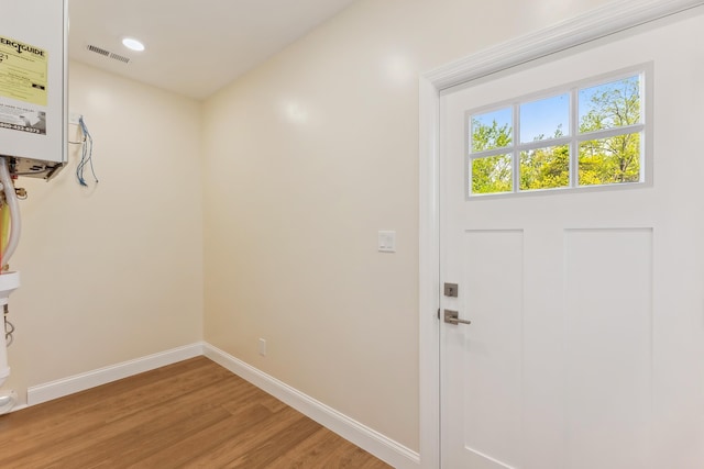 doorway to outside featuring visible vents, light wood-style floors, water heater, and baseboards