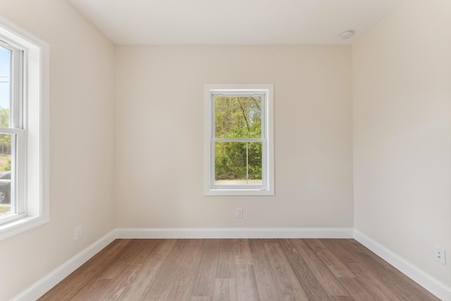 empty room with a healthy amount of sunlight, baseboards, and light wood-type flooring