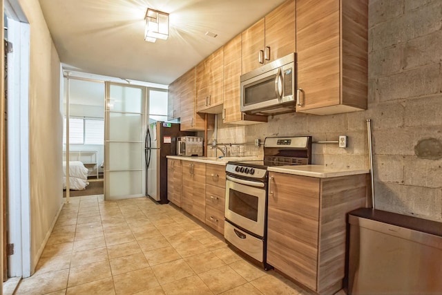 kitchen with appliances with stainless steel finishes, light tile patterned floors, and sink