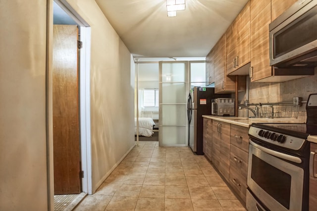 kitchen featuring tasteful backsplash, sink, light tile patterned floors, and stainless steel appliances