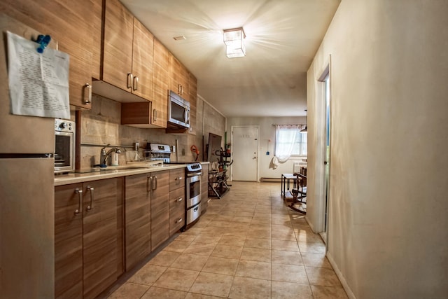 kitchen with appliances with stainless steel finishes, light tile patterned floors, and sink