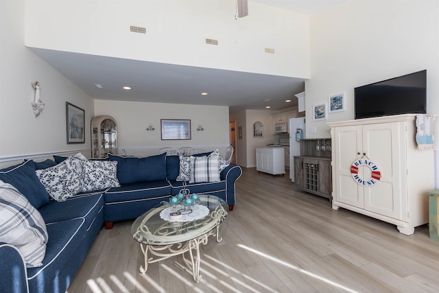 living room with a towering ceiling and light hardwood / wood-style floors