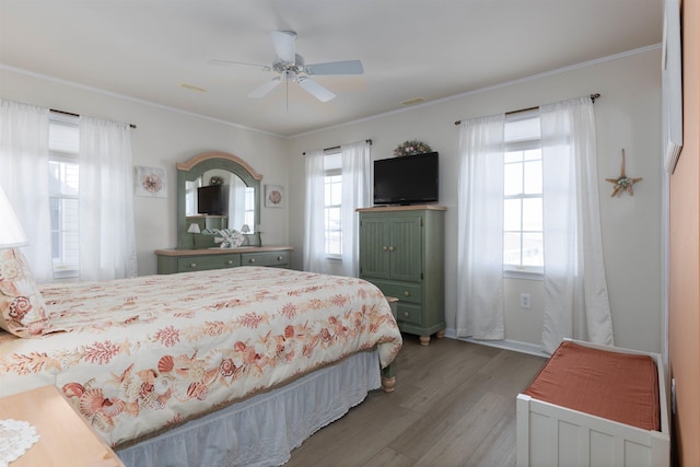 bedroom with multiple windows, ornamental molding, ceiling fan, and light wood-type flooring