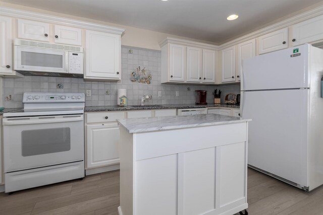 kitchen with light hardwood / wood-style flooring, a kitchen island, white cabinets, white appliances, and backsplash