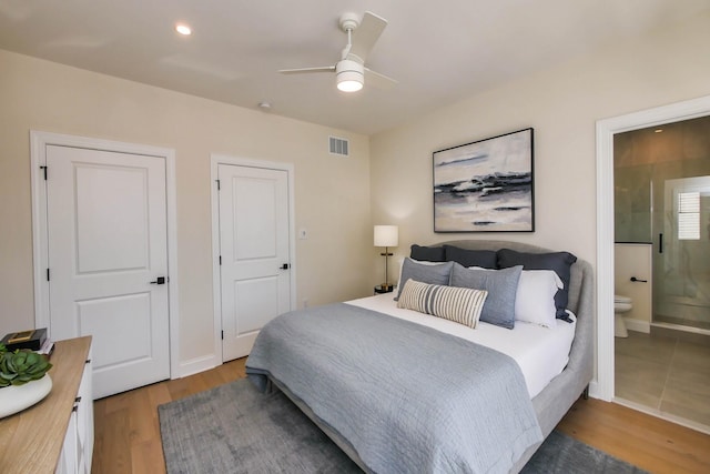 bedroom with wood finished floors, visible vents, baseboards, recessed lighting, and ensuite bathroom