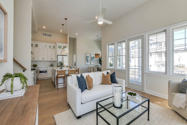 living area featuring visible vents, a healthy amount of sunlight, light wood-type flooring, and a ceiling fan