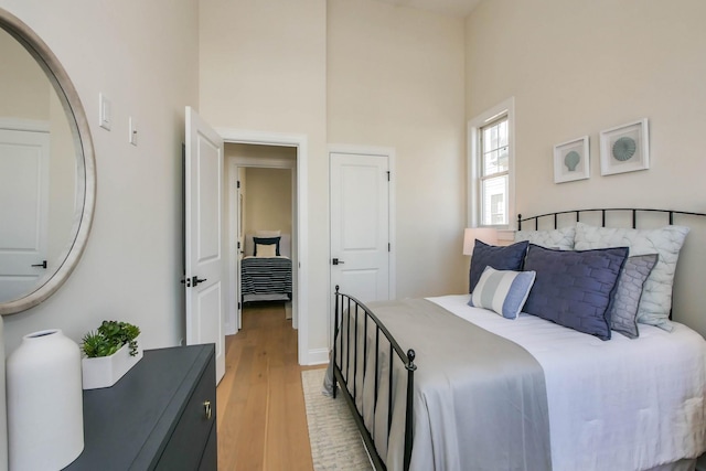 bedroom featuring a towering ceiling and light wood finished floors