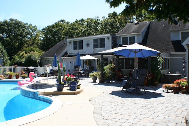 rear view of house with a patio area and a pool with hot tub