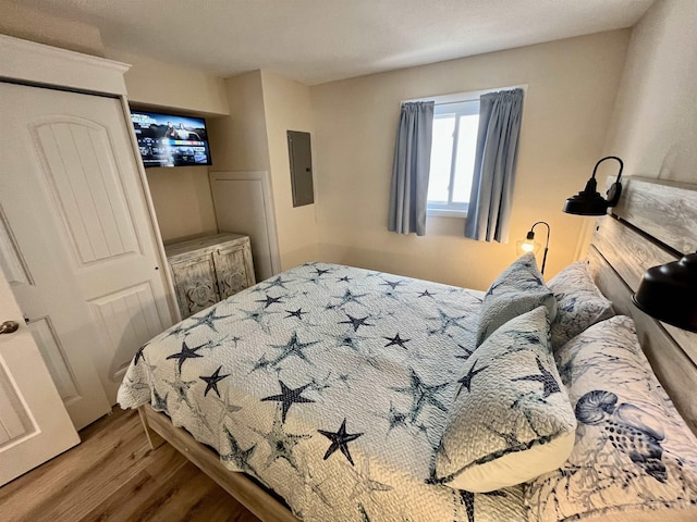 bedroom with electric panel and wood finished floors