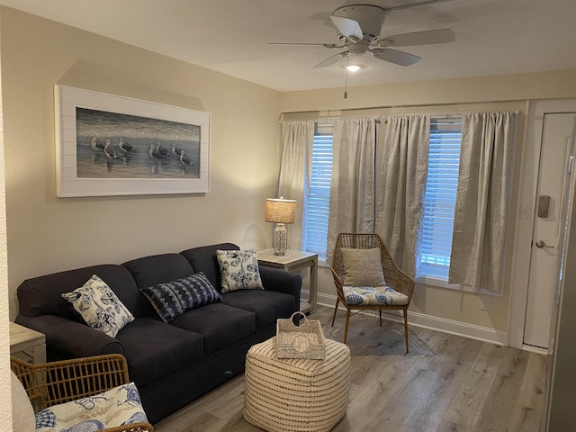 living room with ceiling fan, baseboards, and wood finished floors