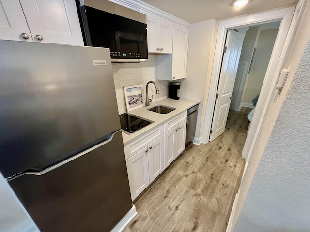 kitchen featuring a sink, white cabinetry, appliances with stainless steel finishes, light wood-type flooring, and decorative backsplash