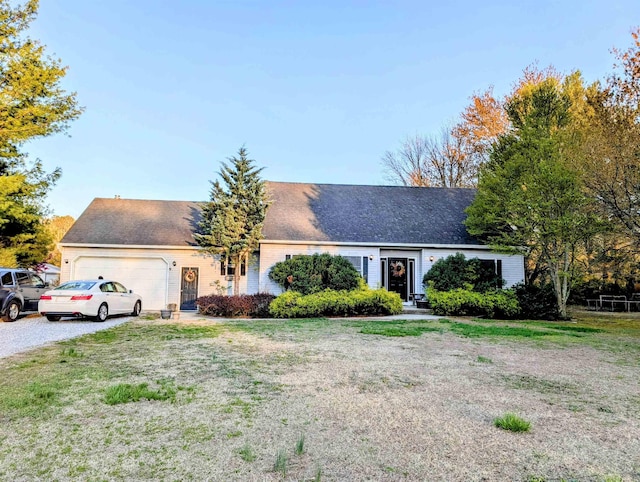 ranch-style house featuring an attached garage, driveway, a front lawn, and roof with shingles