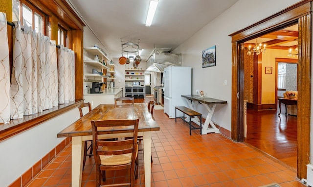 dining space featuring tile patterned floors, built in shelves, and an inviting chandelier