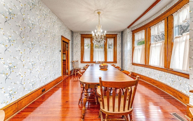 dining area with a notable chandelier, wood-type flooring, and a textured ceiling