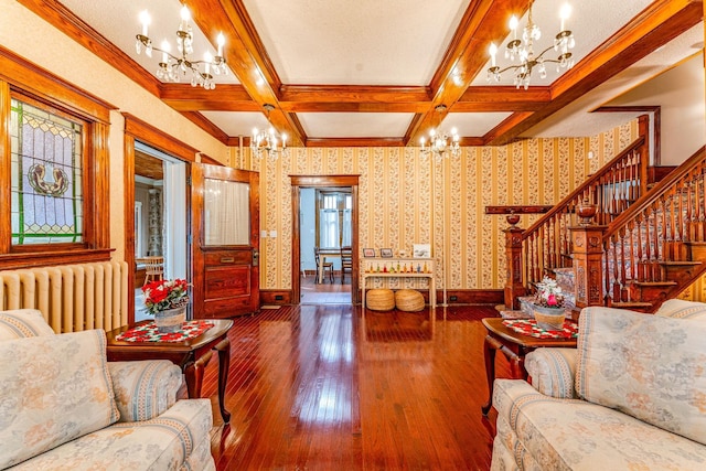 living room with coffered ceiling, radiator heating unit, beamed ceiling, wood-type flooring, and a chandelier