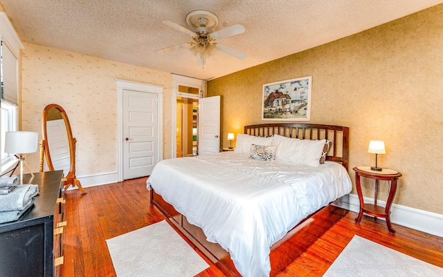 bedroom featuring ceiling fan, dark wood-type flooring, and a textured ceiling