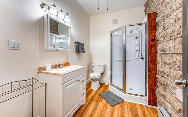 bathroom with hardwood / wood-style floors, vanity, toilet, and walk in shower