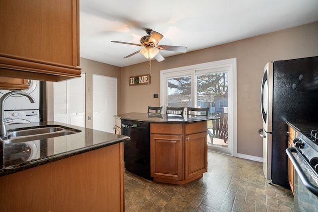 kitchen featuring black dishwasher, a ceiling fan, gas stove, dark stone countertops, and brown cabinetry