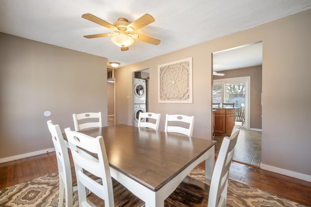 dining room with baseboards, ceiling fan, stacked washing maching and dryer, and wood-type flooring