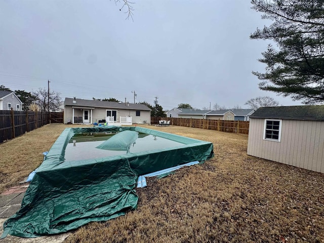 view of yard with an outbuilding, a storage unit, a fenced backyard, and a fenced in pool