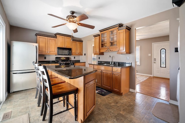 kitchen featuring visible vents, dark countertops, a ceiling fan, a sink, and black appliances